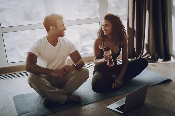 A Couple Sitting On Gym Carpet With Laptop. Healthy Lifestyle. Shape Sportswear. Attractive Athlete. Physical Healthcare. Help Each Other. Have A Break. Yoga Position. Morning Fitness.