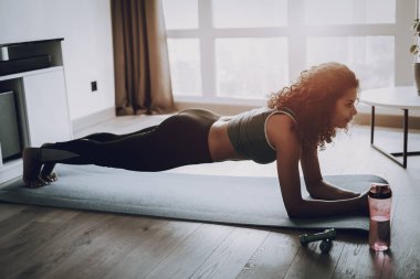 Afro Amerikan Genç kız. Ev Fitness kavramı. Sabah egzersizleri. Aerobik antrenmanın. Slim Fit. Sağlıklı bir yaşam tarzı. Spor giyim şekli. Çekici atlet. Fiziksel sağlık. Spor salonu halı.