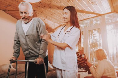 Emekli go-kart üzerinde. Bakıcı. Yetişkin beyaz. Asyalı hemşire. Yardımcı olur. Yetişkin Walker. Bakım evi. Sert kendisini gidin. Doktor destekler adam hemşire tutun. Yaşlı kemikler. Sandalye gün. Emekli oldu. Medikal tedavi.