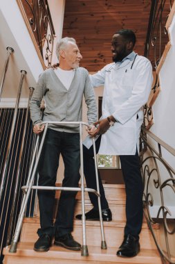 Doktor yardımcı olur. Emekli go-kart üzerinde. Bakıcı. Git. Merdiven. Bakım evi. Adam tutar. Walker yetişkinler için. Yalnız yürümeyeceksin zor. Adam yetişkin beyaz destekler. Yaşlı kemikler. Sandalye gün. Emekli.