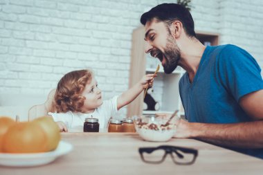 Adam geçirdiği zaman. Bebek besleme babasıdır. Çocuk. Mutlu birlikte. Çocuk Chair.Leisure zamanında. Portakal. Gevreği süt ile. Delisious yiyecek. Kahvaltı. Jam gülümseme. Ev zamanı. Narenciye.