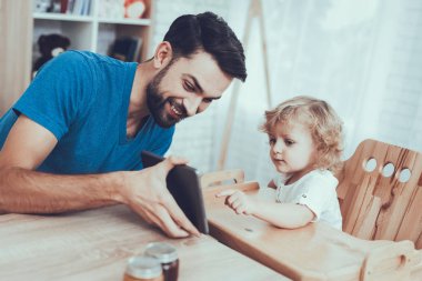 Tablet. Çocuk koltuğu. Jam gülümseme. Mutlu birlikte. Zaman harcıyor. Serbest zaman. Portakal. Gülümseyen çocuklar. Baba. Gevreği süt ile. Delisious yiyecek. Babası iki çocuklar. Kahvaltı. Adam ev zaman.
