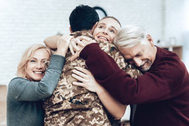 Askerlik hizmeti üzerinden bir adam geri döner. Aile toplantısı. Savaştan bırakarak. Aile ile kucaklamak. Kamuflaj üniforma. Aile asılı. Gösterilen duygular. Vatansever dönüş. Asker duygu.