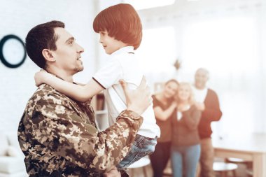 Askerlik hizmeti üzerinden bir adam geri döner. Aile toplantısı. Savaştan bırakarak. Aile ile kucaklamak. Kamuflaj üniforma. Asılı evlat. Gösterilen duygular. Vatansever dönüş. Asker duygu.