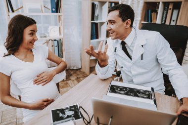 Gülümseyerek. Danışma. Hastane. Hamile kadın. Doktorun ofisinde. Kliniği. Jinekolog. Beyaz önlük. Doktor. Kliniği. Annelik. Dizüstü bilgisayar. Ultrason. Tıbbi yardım. İyi eğlenceler. Doğum sırasında. Göbek. Fan.
