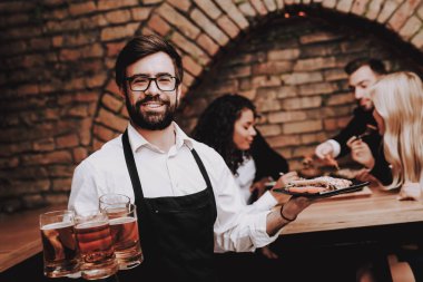 Bira ve aperatifler. Sakallı barmen. İyi eğlenceler. Birlikte. Kızlar ve çocuklar. Bar. Genç insanlar. Dinlenme. Alkol. Farklı ırklardan iletişim. Clubbing. Gece hayatı. Neşeli. Boş zaman. Olumlu. Duygu.