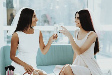 Kızlar tavuk taraf şampanya içiyor. Düğün öncesi kavramı. Güzel parlak gülüş. Gelinle dinleniyor. Güneşli bir gün. İyi bir ruh hali. Genç ve çekici. Mutlu tatil. Uzun saç.