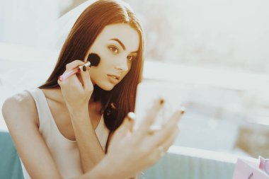 Gülümseyen kız tavuk taraf önce bir makyaj yapıyor. Düğün öncesi bakım kavramı. Güzel parlak gülüş. Aynaya bak. Güneşli bir gün. İyi bir ruh hali. Genç ve çekici. Mutlu tatil. Uzun saç.