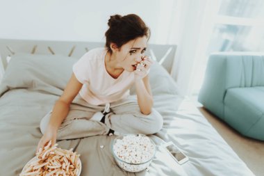 Ağlayan kadın kızarmış patates ve patlamış mısır yiyor. Mutsuz tatil. Üzücü hafta sonu. Gözyaşları yüzünde. Güneşli bir gün. Yatak odasında yalnız. Hayal kırıklığına kız. Şımarık makyaj. Akan maskara.