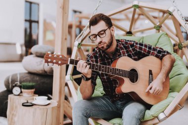Gitar. Kahve. Fikirler oluşturun. İlham. Yaratıcı işçi. Sandalyeye asılı. Otur. Beyin fırtınası. Genç bir adam. İş adamı. Ofiste çalışıyor. İş adamları. Çalışma alanı. Gevşeme. Rahat.