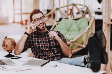 Oh telefonda. Ayakları üzerinde tablo. Rahat. İlham. Küre. Proje. Dizüstü bilgisayar. Otur. Beyin fırtınası. Genç bir adam. İş adamı. İş. Office. Yaratıcı işçi. Fikirler. İş adamları. Çalışma alanı.