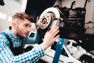 Genç makinist garajında Otomotiv Hub onarır. Profesyonel üniforma. Servis istasyonu kavramı. Kendine güvenen mühendis bakışları. Ayrıntı onarılıyor. Aracın altında. Otomobil Tanı.