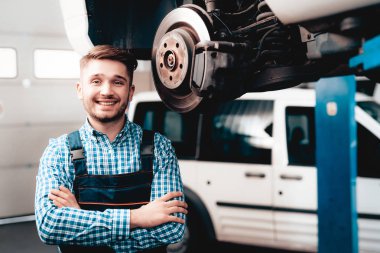 Genç makinist anahtar garajda ile poz. Profesyonel üniforma. Servis istasyonu kavramı. Kendine güvenen mühendis bakışları. Ayrıntı onarılıyor. Aracın altında. Otomobil Tanı.