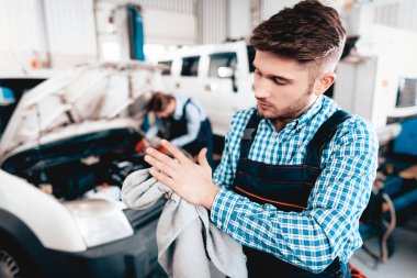 Genç otomatik mekanik mendil havlu garajında elleriyle. Servis istasyonu kavramı. Birlikte çalışıyor. Araba anahtarı ile Reparing. Mühendislik uzmanları. Takım çalışması. Otomobil tanı. Kirli eller.