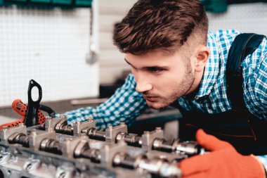 Otomatik mekanik ayrıntı kontrol ediyor. Servis İstasyonu. Profesyonel üniforma. Kendine güvenen Mühendisliği uzmanı bakışları. Koruyucu eldiven. Garajda çalışıyor. Genç tamirci poz kavramı.