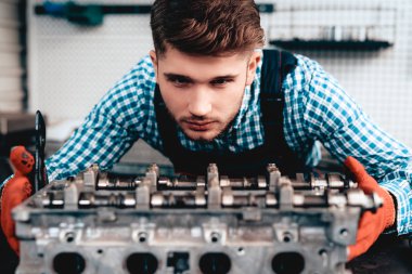 Otomatik mekanik ayrıntı kontrol ediyor. Servis İstasyonu. Profesyonel üniforma. Kendine güvenen Mühendisliği uzmanı bakışları. Koruyucu eldiven. Garajda çalışıyor. Genç tamirci poz kavramı.