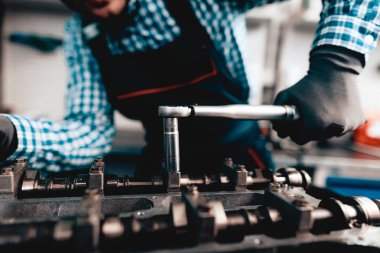 Genç otomatik mekanik katlanmış bir somun. Servis istasyonu kavramı. Kullanarak anahtarı. Detay Reparing. Profesyonel üniforma. Kendine güvenen mühendislik uzmanı. Koruyucu eldiven. Garajda çalışma.