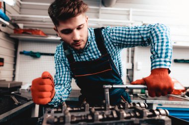 Genç otomatik mekanik katlanmış bir somun. Servis istasyonu kavramı. Kullanarak anahtarı. Detay Reparing. Profesyonel üniforma. Kendine güvenen mühendislik uzmanı. Koruyucu eldiven. Garajda çalışma.