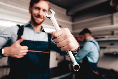 Otomatik mekanik anahtar ile poz. Servis İstasyonu. İş arkadaşı bir arka plan üzerinde. Kendine güvenen bakışları. Gülümseyen iş arkadaşları. Profesyonel mühendisleri üniforma. Bir garajda çalışıyor. Neşeli Master.