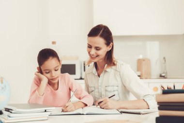 Anne kızı mutfakta ödev yapmak için yardımcı olur. Aile ilişki kavramı. Eğitim çocukluk. Evde eğitim. Bilgi alma. Bilgi yazma. Ebeveynler görev. Birlikte çalışma.