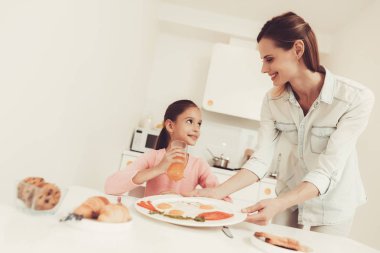 Anne mutfakta kızı A kahvaltı veriyor. Mutlu aile ilişki kavramı. Yemeye hazır. Sabah Nutricion. Mutfak masasında. Bıçak ve çatal. Tabak yemek ile. Sağlıklı gıda.