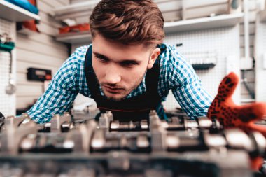 Otomatik mekanik ayrıntı kontrol ediyor. Servis İstasyonu. Profesyonel üniforma. Kendine güvenen Mühendisliği uzmanı bakışları. Koruyucu eldiven. Garajda çalışıyor. Genç tamirci poz kavramı.