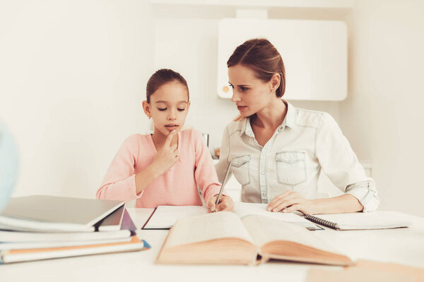 Mom Helps Daughter To Do Homework In The Kitchen. Family Relationship Concept. Educational Childhood. Studying At Home. Knowledge Receiving. Information Writing. Parents Duty. Working Together.
