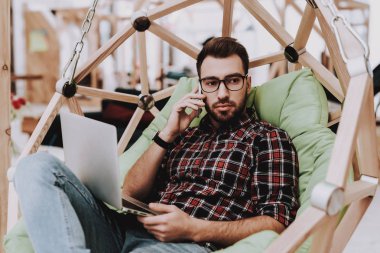 Sandalyeye asılı. Dizüstü bilgisayar. Otur. Beyin fırtınası. Genç bir adam. İş adamı. Ofiste çalışıyor. Yaratıcı işçi. Fikirler oluşturur. İş adamları. Çalışma alanı. İlham. Gevşeme. Rahat Office.