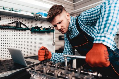 Genç otomatik mekanik katlanmış bir somun. Servis istasyonu kavramı. Kullanarak anahtarı. Detay Reparing. Profesyonel üniforma. Kendine güvenen mühendislik uzmanı. Koruyucu eldiven. Garajda çalışma.