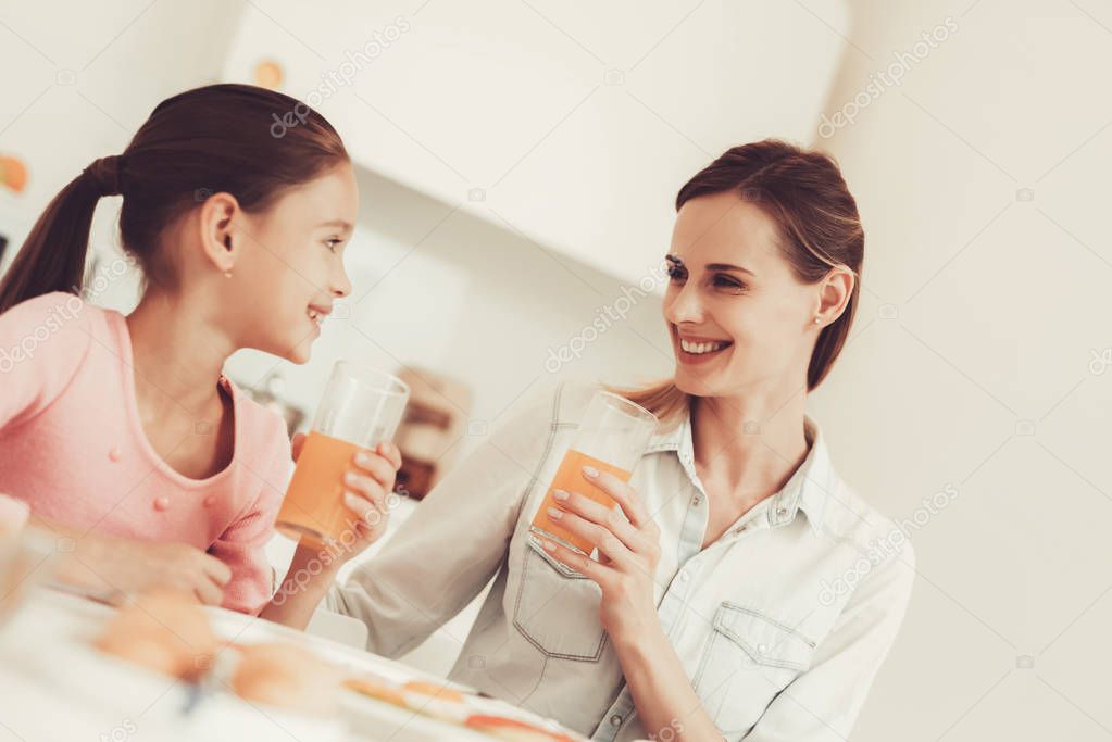 Mom With Daughter Are Having A Dinner At Kitchen. Family Relationship Concept. Having Fun During The Breakfast. Morning Nutricion. Juice Drinking. Happy Childhood Concept. Time To Lunch.