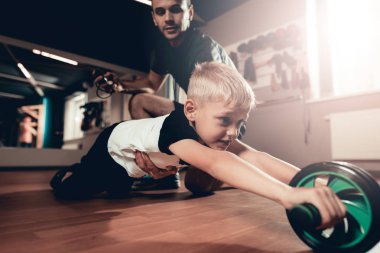 Sportif çocuk spor tekerlek ile çalışmaları yapıyor. Ebeveynlik ilişki. Sportif aile kavramı. Aktif yaşam tarzı. Egzersiz tuşuna basın. Holiday Leisure. Birlikte çalışma dışarı. Fitness gün.