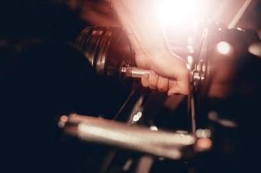 Yakın çekim. Metal bir Dumbbell toplama el görünümünü. Fitness gün. Pazı egzersiz. Aktif yaşam tarzı. Eğitim kavramı. Holiday Leisure. İş vakti. Spor salonu ekipman. Güneş ışığı. Sağlık.
