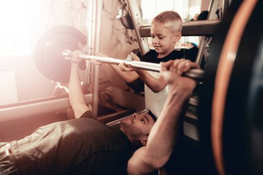 Baba-halter kaldırma sırasında oğlu destek. Ebeveynlik ilişki. Sportif aile kavramı. Aktif yaşam tarzı. Dayanıklılık egzersiz. Holiday Leisure. Birlikte çalışma dışarı. Fitness gün.