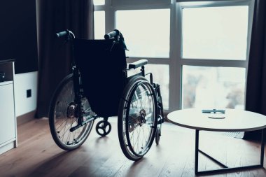 Modern boş tekerlekli sandalye Oda penceresinde yakın dur. Siluet siyah geçersiz sandalye Engelli insanlar Park içinde parlak hastalar Salon yakınındaki geniş panoramik pencere için.