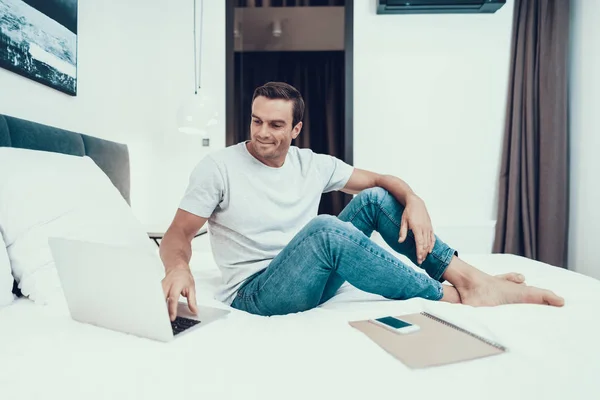 Schöner Mann Der Auf Dem Bett Sitzt Und Laptop Arbeitet — Stockfoto
