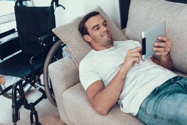 Mann Entspannt Auf Sofa Mit Tablet Der Nähe Rollstuhl Fröhlich — Stockfoto