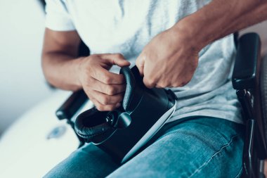 Portre, Engelli Vr gözlük koyarak adam. Erkek kişi kapalı pencere giyer yakınındaki tekerlekli sandalyede rahat kıyafetler oturur. Adam tutarak ellerinde ve gidiş sanal gerçeklik kulaklık takmak