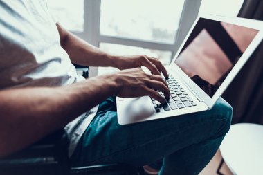 Erkek el üstünde Laptop klavye yazarak closeup. Tanınmayan kişi T-Shirt giyiyor ve tekerlekli sandalye ağ kucağına defter tutan kot oturur. Sakatlık ve iş kavramı
