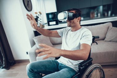 Engelli adam Vr kulaklık giyen tekerlekli sandalyede. Sanal gerçeklik gözlükleri ve yayılır eller iki taraf için de mutlu bir insan oturur büyük aydınlık oturma odası giyer rahat kıyafetler portresi sahiptir