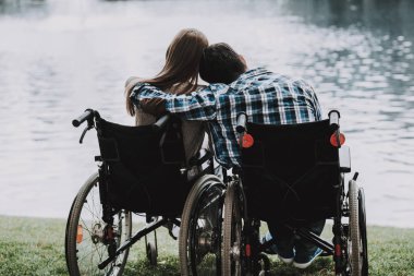 Engelli insanlar üzerine tekerlekli sandalye yaptı Lake Park yakınındaki. Genç adam kadın tekerlekli sandalye üzerinde devre dışı. Yaz Park'ta rahatlatıcı. Eğlenceli yaz Park. Kurtarma ve sağlık kavramları. Neşeli insanlar.