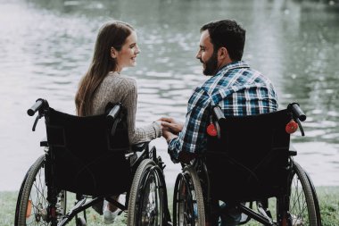 Engelli insanlar üzerine tekerlekli sandalye yaptı Lake Park yakınındaki. Genç adam kadın tekerlekli sandalye üzerinde devre dışı. Yaz Park'ta rahatlatıcı. Eğlenceli yaz Park. Kurtarma ve sağlık kavramları. Neşeli insanlar.