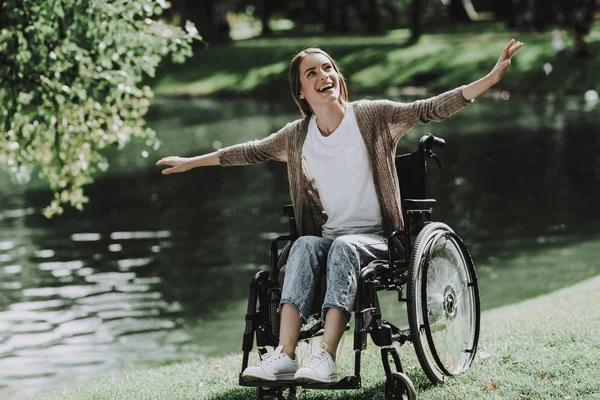 在湖边的公园里坐轮椅的年轻微笑的女孩 残疾的年轻女子 在夏季公园放松身心 夏季公园的乐趣 恢复和医疗保健概念 坐着的女人 湖公园 — 图库照片