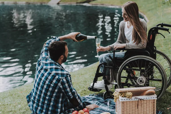 女孩在轮椅与男子在公园野餐 残疾的年轻女子 轮椅上的女人在夏季公园放松身心 夏季公园野餐 恢复和医疗保健概念 开朗的人 — 图库照片