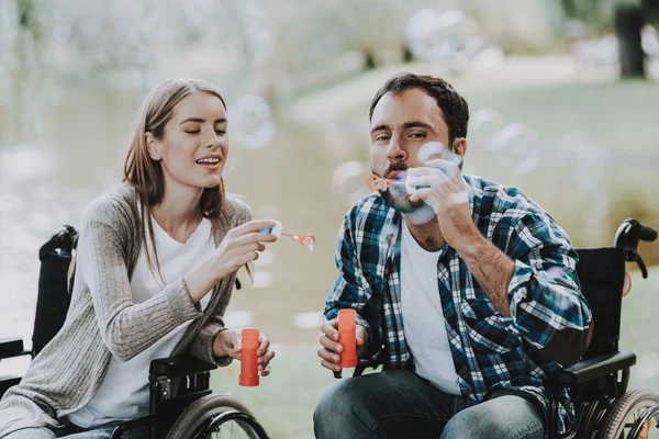 Disabled People on Wheelchairs Have Fun in Park. Disabled Young Man. Woman on Wheelchair. Relaxing in Summer Park. Fun in Summer Park. Recovery and Healthcare Concepts. Cheerful People.