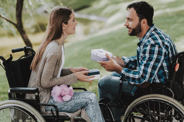 几个残疾人在公园里交换礼物 轮椅上残疾的年轻男子妇女 在夏季公园的日期 浪漫的关系 恢复和医疗保健概念 快乐夫妇 — 图库照片