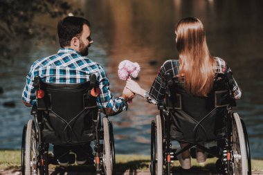 Engelliler tekerlekli sandalye Park Tarih üzerinde birkaç. Çiçekler olan genç adam. Tekerlekli sandalye kadınlarda. Tarih yaz Park. Romantik ilişki. Kurtarma ve sağlık kavramları. Mutlu çift.