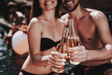 Gülümseyen iki havuz, alkollü içecekler. Portre, güzel genç bira şişe tutan ve having Fun havuz kenarında çift. Mutlu arkadaş Enoying havuz partisi. Yaz tatili kavramı