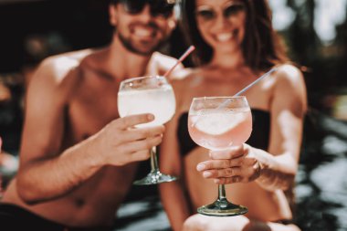 Gülümseyen iki kokteyller havuz kenarında içme. Güzel genç gözlük alkollü içecekler ile tutarak ve having Fun havuz kenarında çift. Mutlu arkadaş Enoying havuz partisi. Yaz tatili kavramı