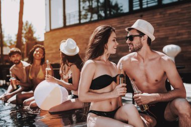 Gülümseyen iki havuz, alkollü içecekler. Güzel genç bira şişe tutan ve having Fun havuz kenarında çift. Mutlu arkadaş Enoying havuz partisi. Yaz tatili kavramı