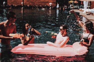 Grup arkadaşıyla genç gülümseyen havuzda eğleniyor. Genç mutlu insanlar iskambil birlikte renkli su silahlar içinde Açık Yüzme Havuzu. Arkadaşlar havuz partisinde. Yaz tatili kavramı